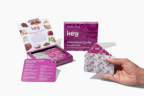 The image shows a dietary supplement product for Key Menstrual Cycle, with packaging that includes a box and a blister pack with tablets. A hand is holding the blister pack.
